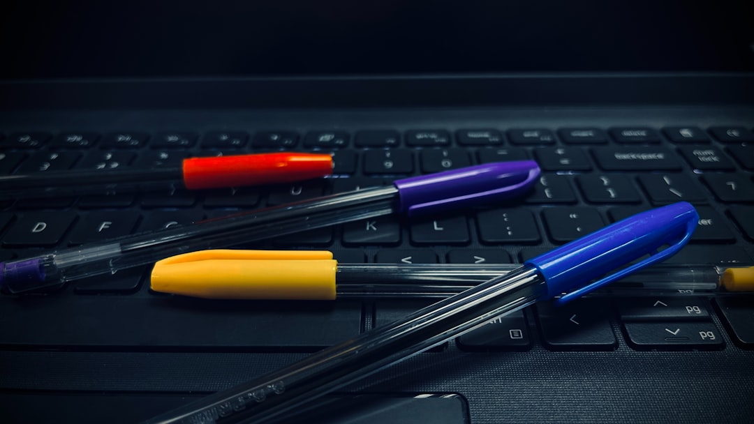 three pens sitting on top of a laptop keyboard
